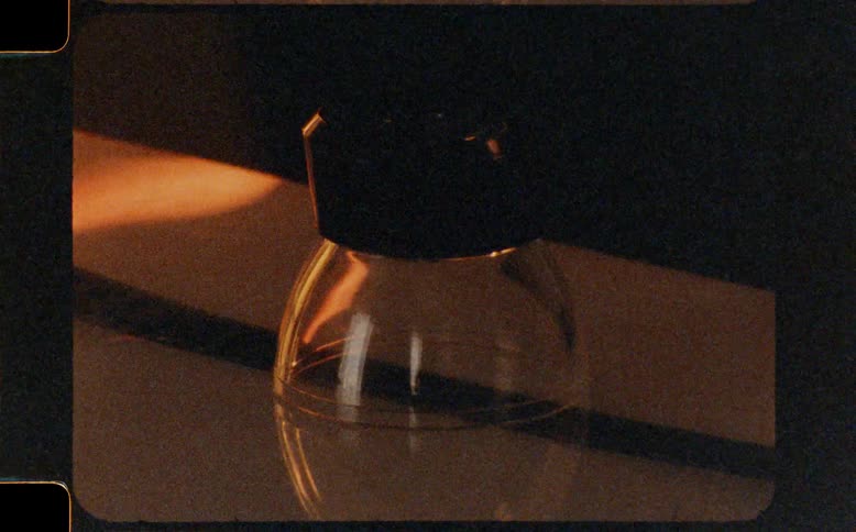 A vintage Super 8 film captures a dramatic close-up of a film editor's loupe on a strip of film