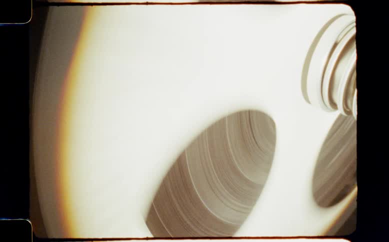 Extreme close-up of a vintage film reel spinning on a projector with a prominent film gate border