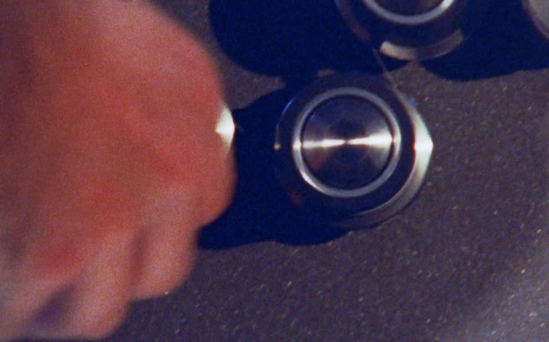 A close-up shot of a person's hands carefully threading a strip of film through a vintage editing machine