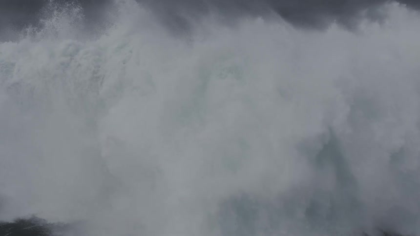 A gigantic, powerful ocean wave forms and breaks in dramatic, super slow motion