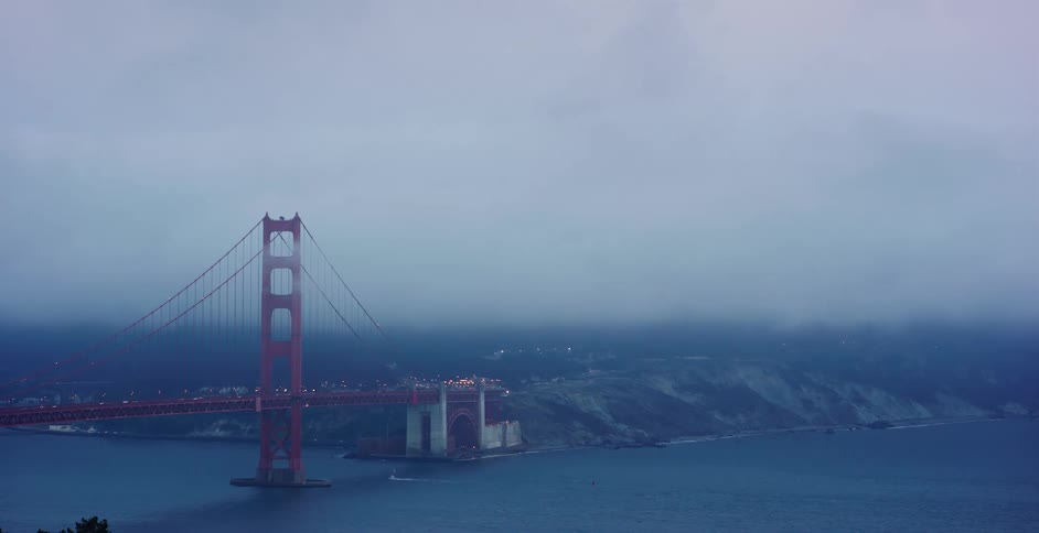 An atmospheric wide shot of the Golden Gate Bridge in San Francisco shrouded in a thick layer of fog