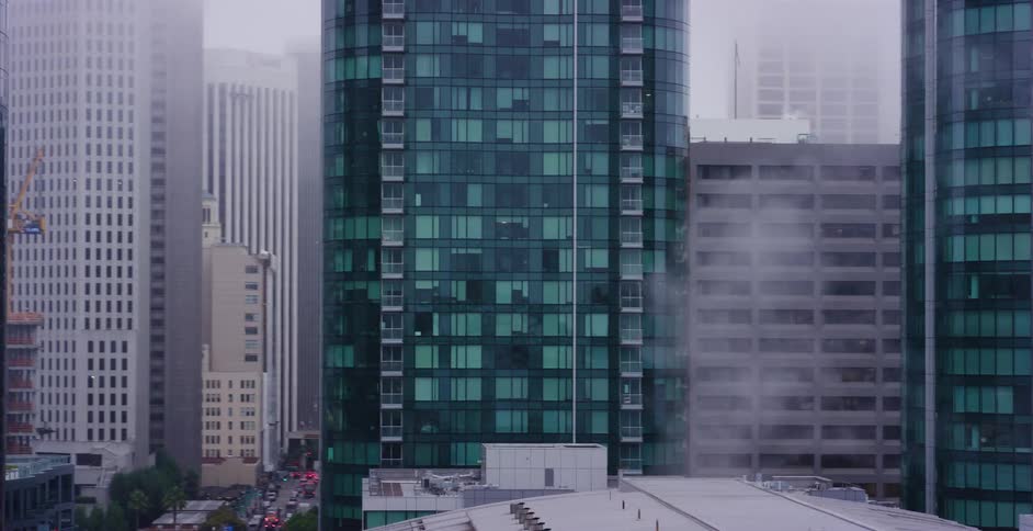 A slow pan reveals a foggy downtown cityscape with steam rising from skyscrapers and a distant construction crane