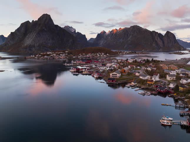 A stunning aerial timelapse of the iconic Reine fishing village in Norway's Lofoten Islands, capturing the transition from a beautiful sunset to tranquil dusk