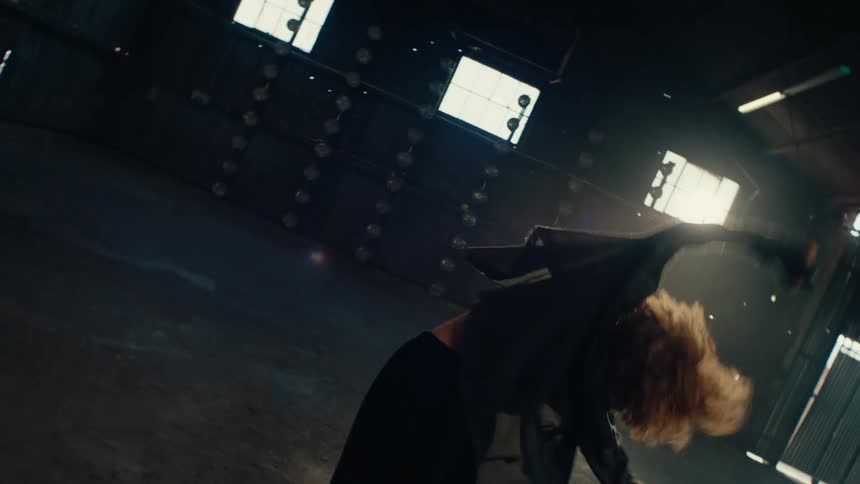 A talented female dancer performs a powerful, expressive contemporary routine in a dark, empty warehouse in slow motion