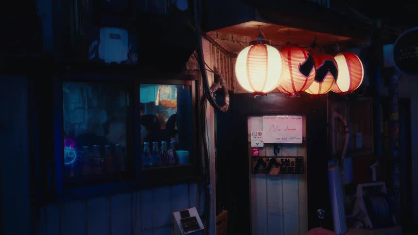Glowing paper lanterns cast a warm light on the entrance to a small Japanese shop in a dark, atmospheric alley at night
