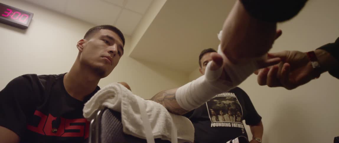 A man bandaging a man's hand while others stand around and watch