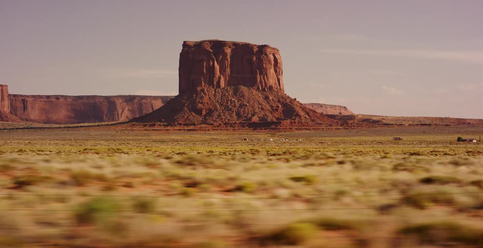 Passing a majestic red rock butte on a scenic drive through the desert landscape of Monument Valley