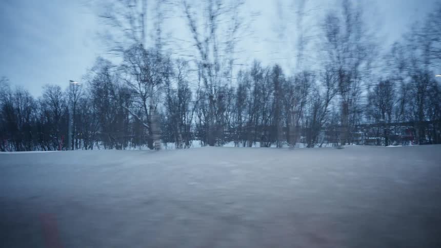 A slow-motion passenger view from a car window of a desolate, snowy landscape passing by on a cold winter day