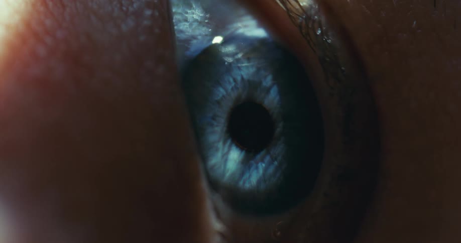 A cinematic macro shot of a vibrant blue human eye blinking slowly