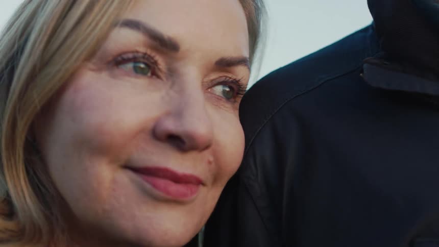 A serene mature woman rests her head on her partner's shoulder, finding comfort and peace in their quiet moment together