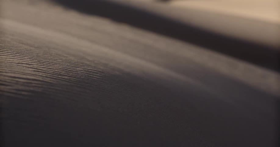 A close-up view shows fine sand being blown by the wind over the textured surface of a dune