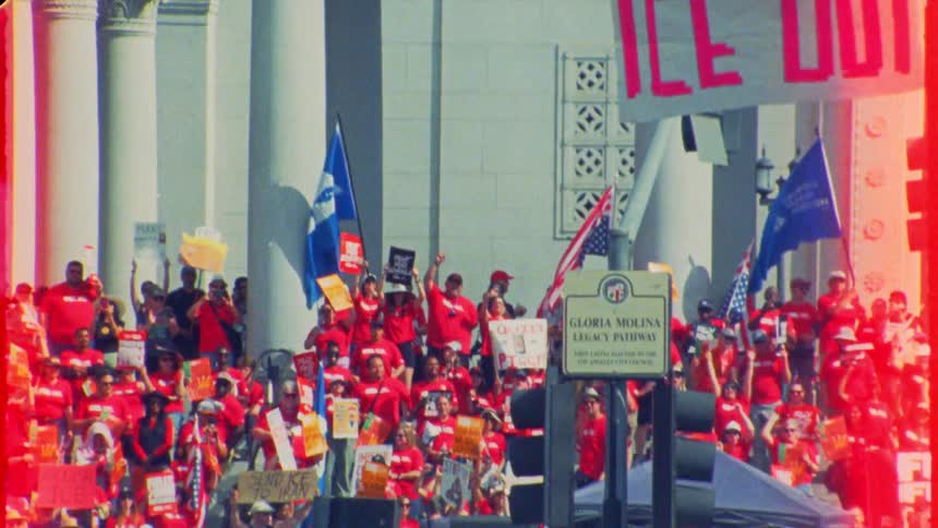 Gritty, vintage-style footage captures a passionate crowd protesting with 'ICE OUT' banners on the steps of a government building