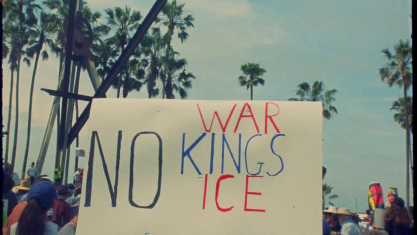 A vintage film shot captures a protest sign reading 'No War, No Kings, No ICE' amidst a crowd under palm trees