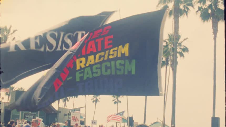 Protest flags with 'Resist' and 'Anti-Trump' messages wave in slow motion with a vintage film aesthetic