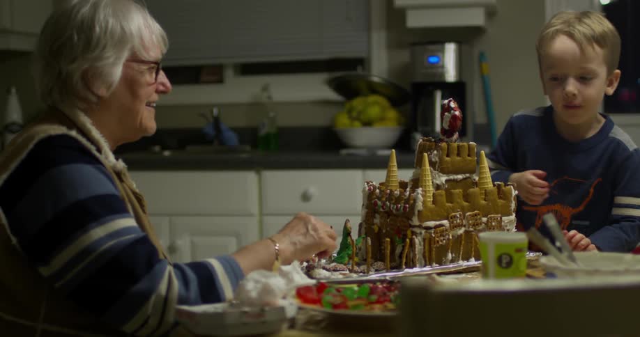 A woman and boy make a gingerbread house