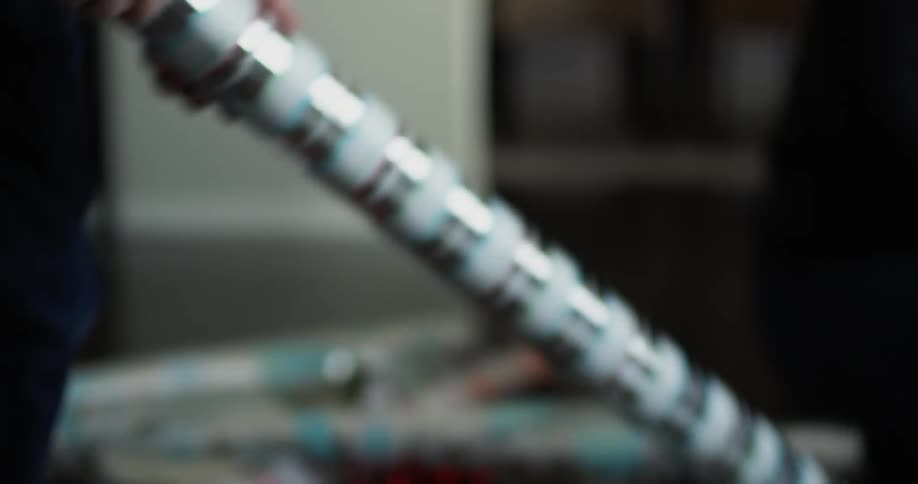 A boy sitting on the floor gets up and gets a roll of wrapping paper