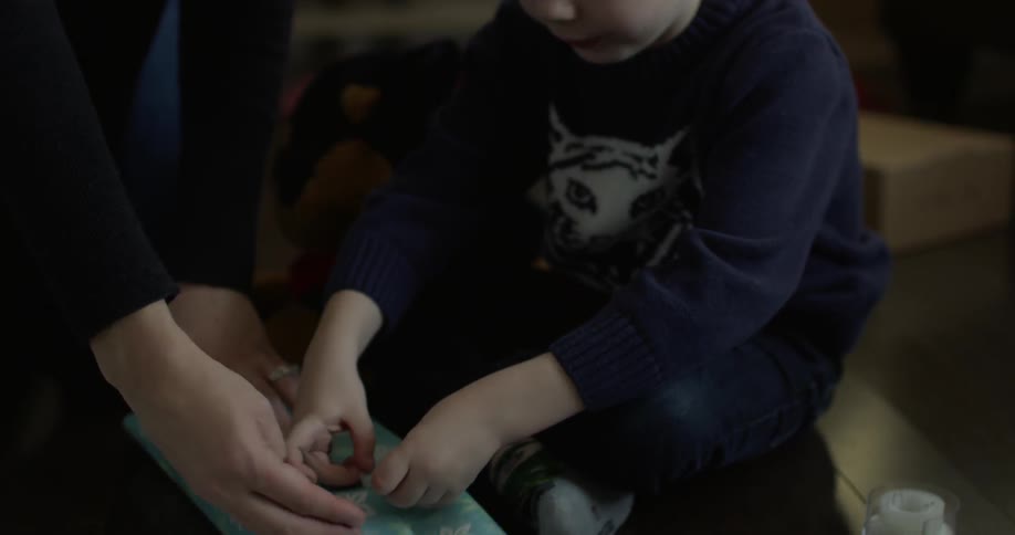Child helping parent wrap a present