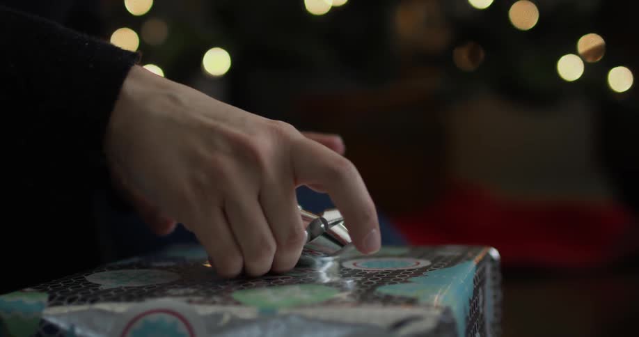 Person puts a bow on top of a wrapped present