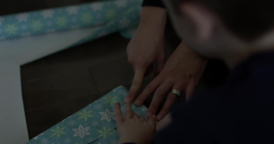 Child helping parent wrap a present