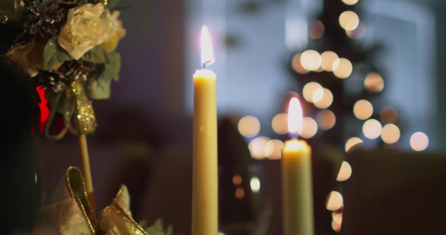 Candles flicker by some christmas decorations