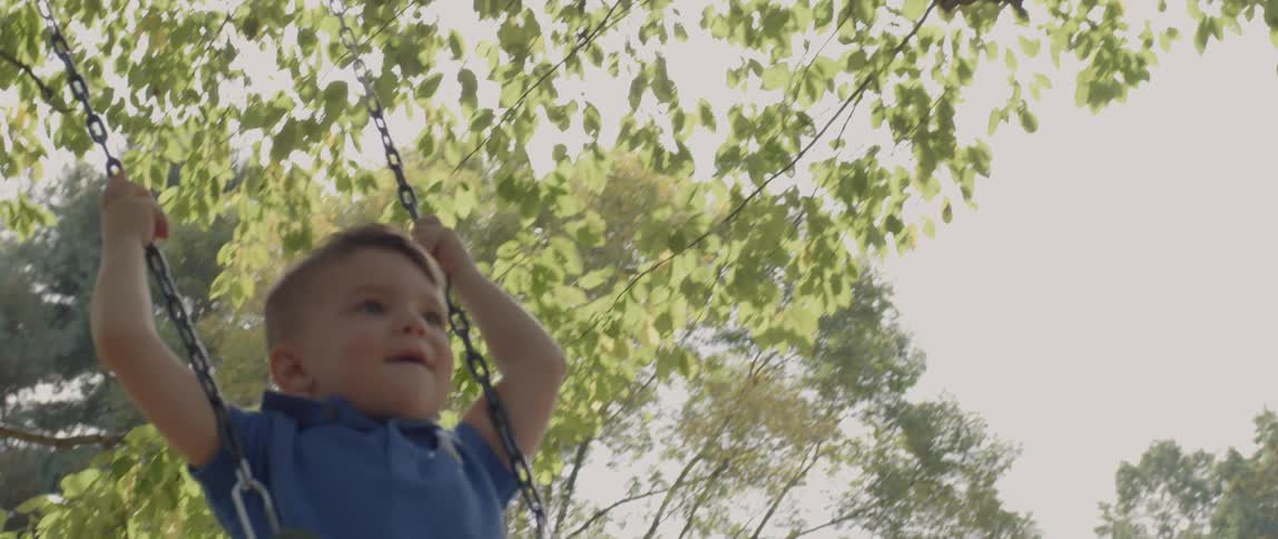 A young boy swings on a sunny day