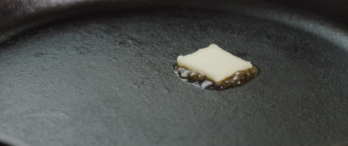 A pat of butter melts in a frying pan