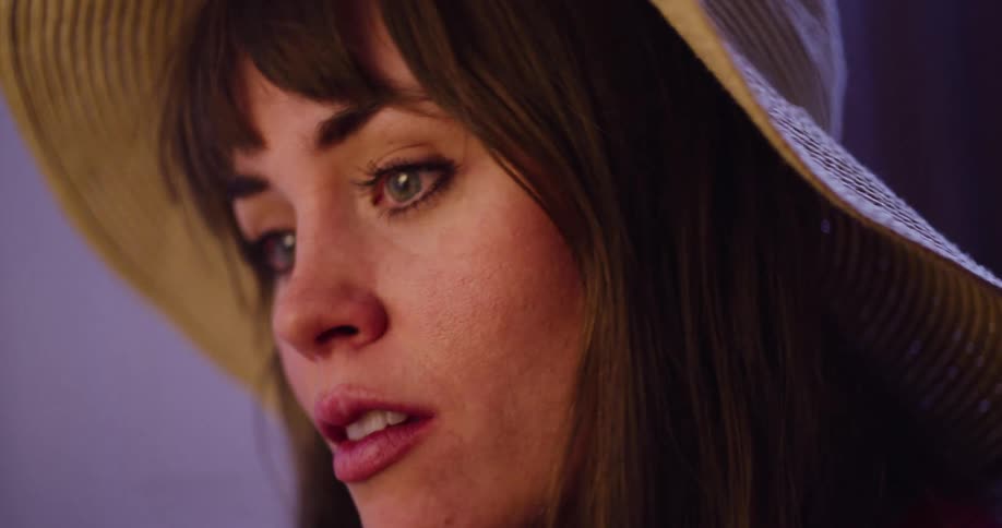 A slow motion close-up shows a beautiful woman in a hat looking down sadly as her eyes well up with tears