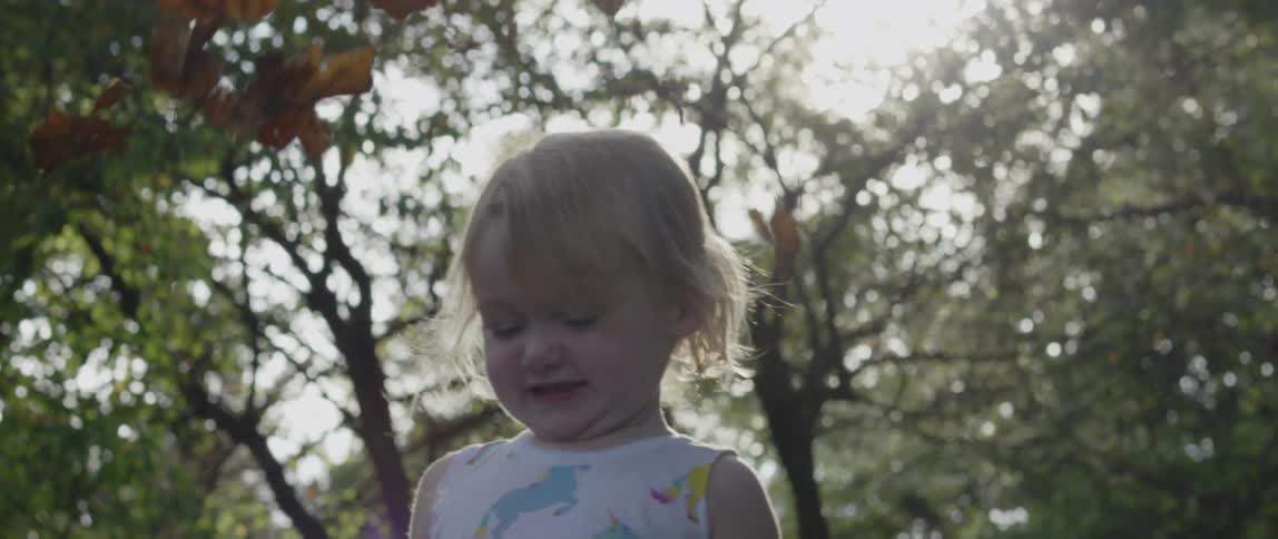 A child throws leaves up into the air