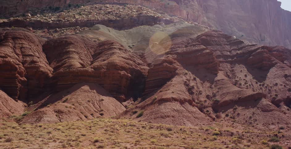 A static shot of the beautifully layered red rock formations in a vast, arid desert canyon under the bright sun