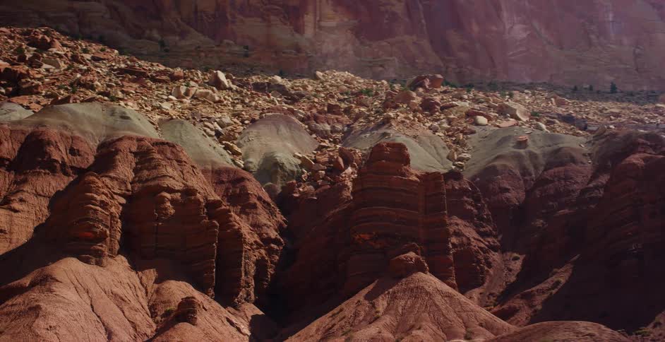 A slow cinematic shot tracks across the majestic layered red rock formations and colorful geology of a vast desert canyon