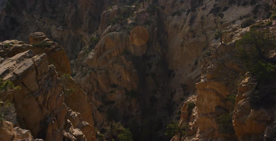 A slow, hazy descent reveals the rugged cliffs and pine trees of a majestic mountain canyon