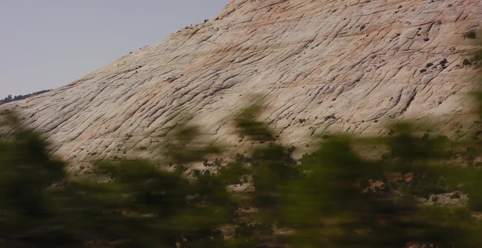 A scenic drive reveals the cracked and textured face of a massive sandstone rock formation in the desert