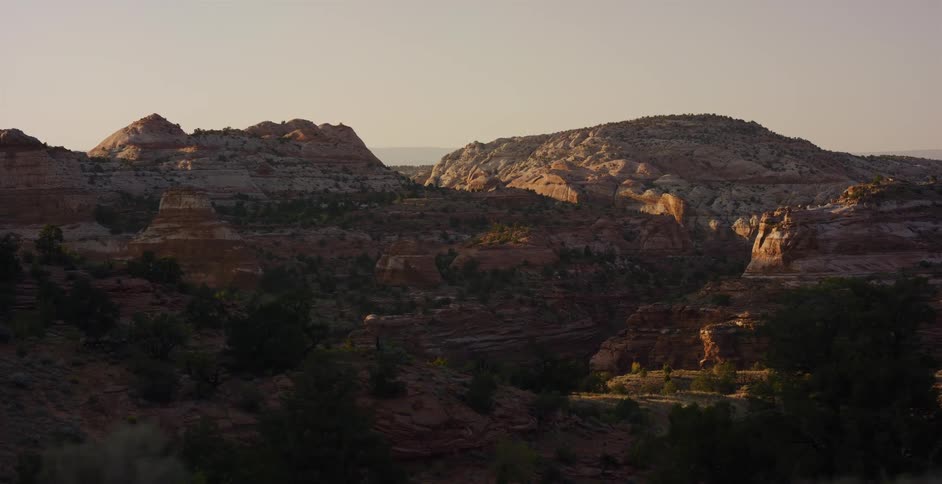 A scenic tracking shot of sun-kissed red rock canyons in a vast desert landscape at golden hour