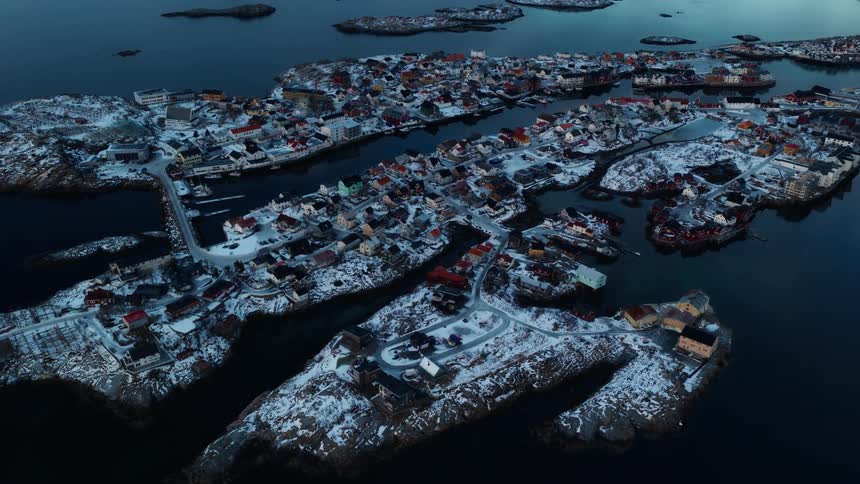 A breathtaking aerial view reveals a charming, snow-covered fishing village spread across interconnected islands during a calm winter twilight
