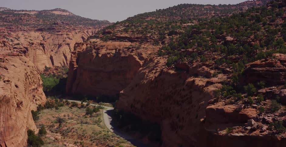 A dramatic reveal of a winding road through a majestic red rock canyon in the desert