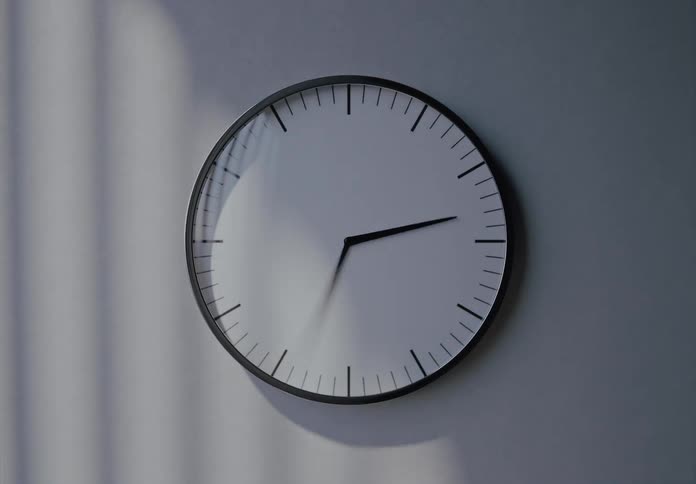 Sunlight and shadows move across a minimalist wall clock in a timelapse, showing the relentless passage of time from morning to night