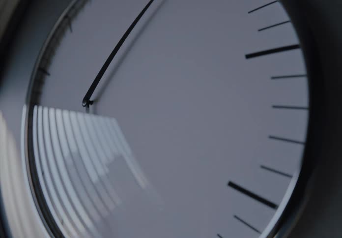 Close-up time-lapse of a minimalist clock face showing the rapid passage of time as light changes from day to night