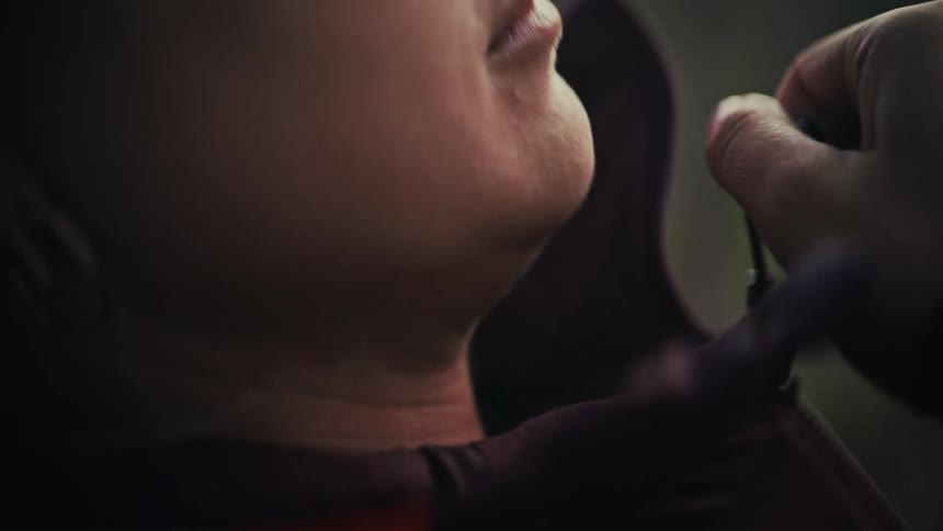 A dramatic slow-motion close-up shows a woman zipping her maroon jacket up to her chin