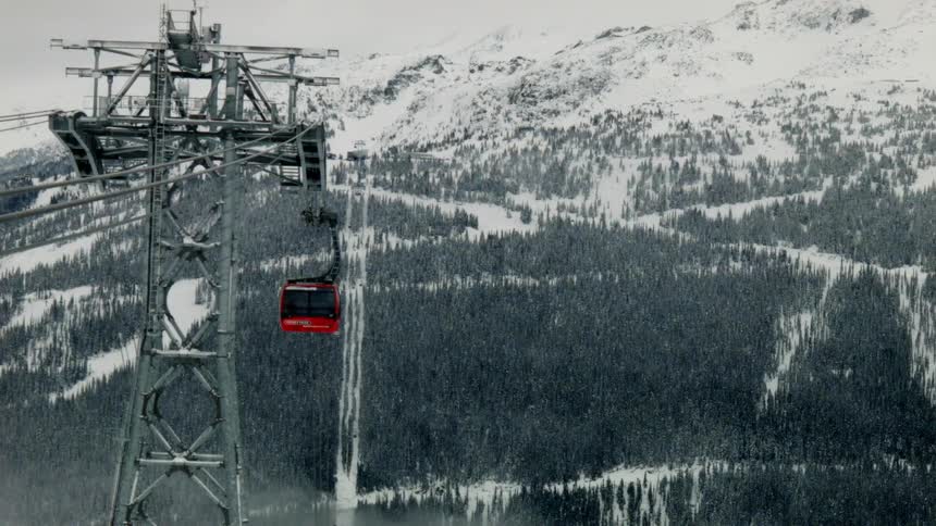 A ski-lift gondola is travelling down toward a valley