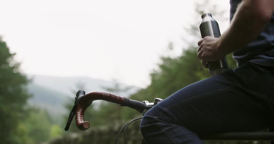 A man drinks from a water bottle as he sits on his bicycle