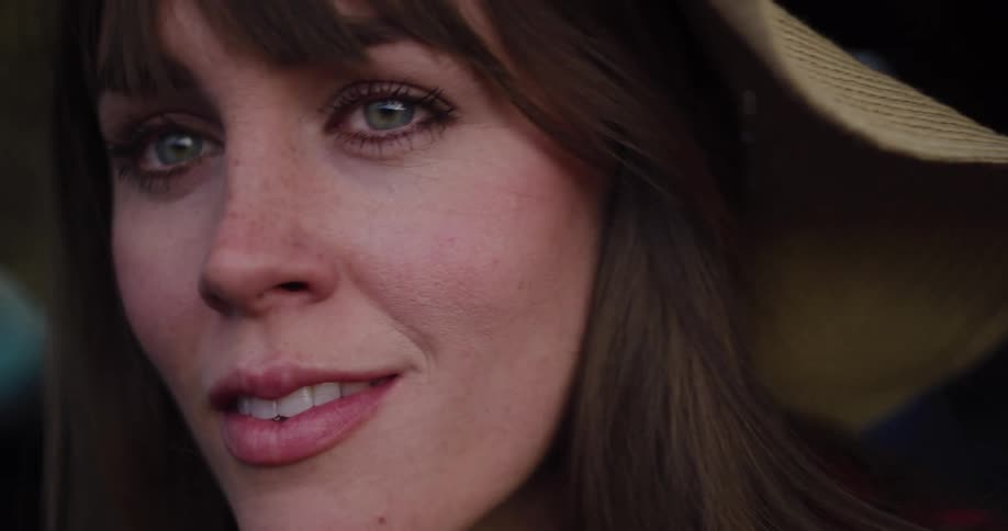 Close-up portrait of a lovely woman with green eyes and a gentle smile, wearing a hat in warm light