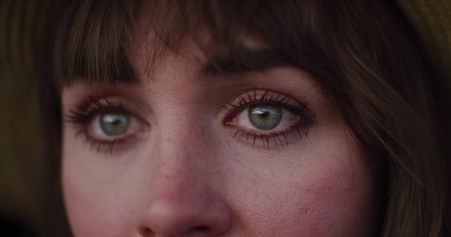 An extreme close-up of a woman's beautiful green eyes welling up with tears as she stares ahead