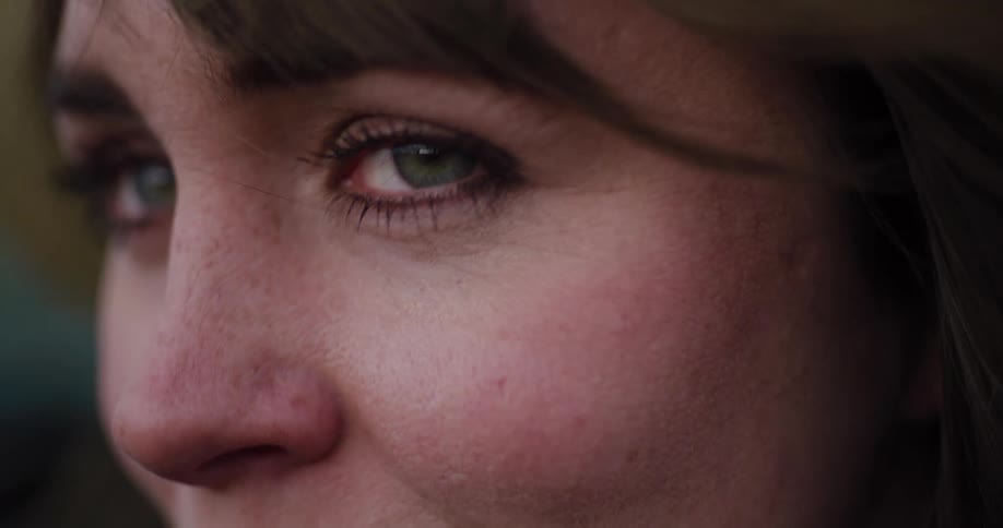 An extreme close-up slow-motion shot of a woman's face, focusing on her emotional green eyes