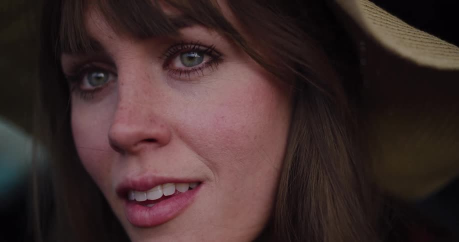 An intimate slow-motion close-up of a thoughtful young woman in a straw hat as she looks away from the camera