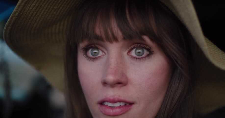 A dramatic close-up of a beautiful woman in a straw hat as she turns to the camera, her wide-eyed expression of surprise softening into a gentle smile