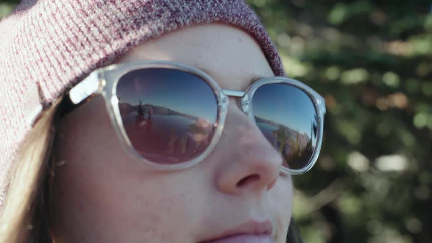 A woman in gray sunglasses stares at the lake