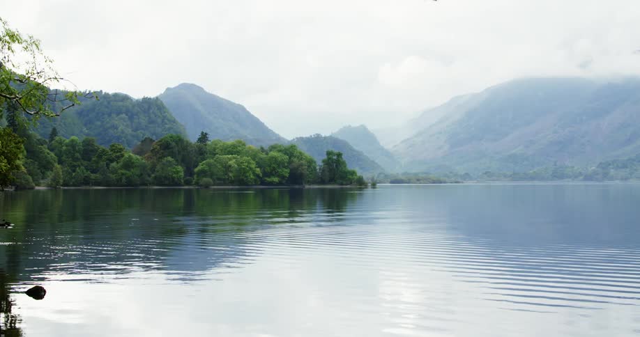 A lake near some trees with mountains in the distance