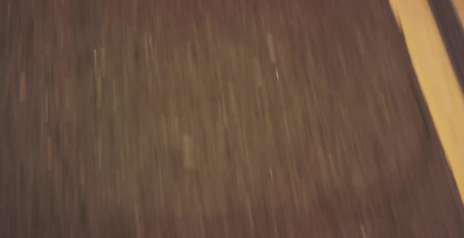 A dynamic reveal shot starts on speeding highway lines and pulls back to show a classic silver Ford Mustang driving along a winding country road