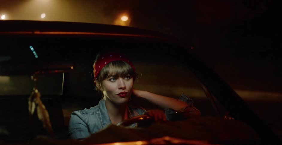 A stylish young woman with a retro look drives a vintage car through the atmospheric city streets at night