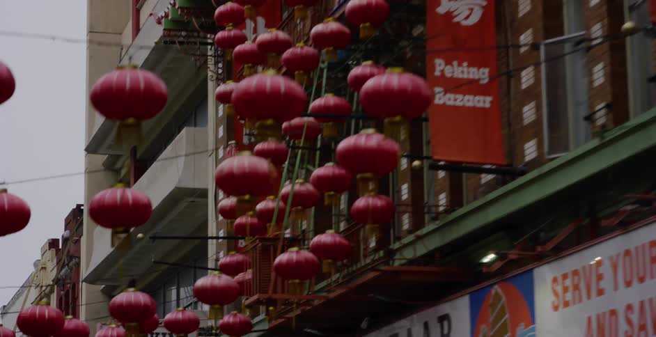 A slow pan reveals traditional red lanterns and signage adorning the buildings in a Chinatown street